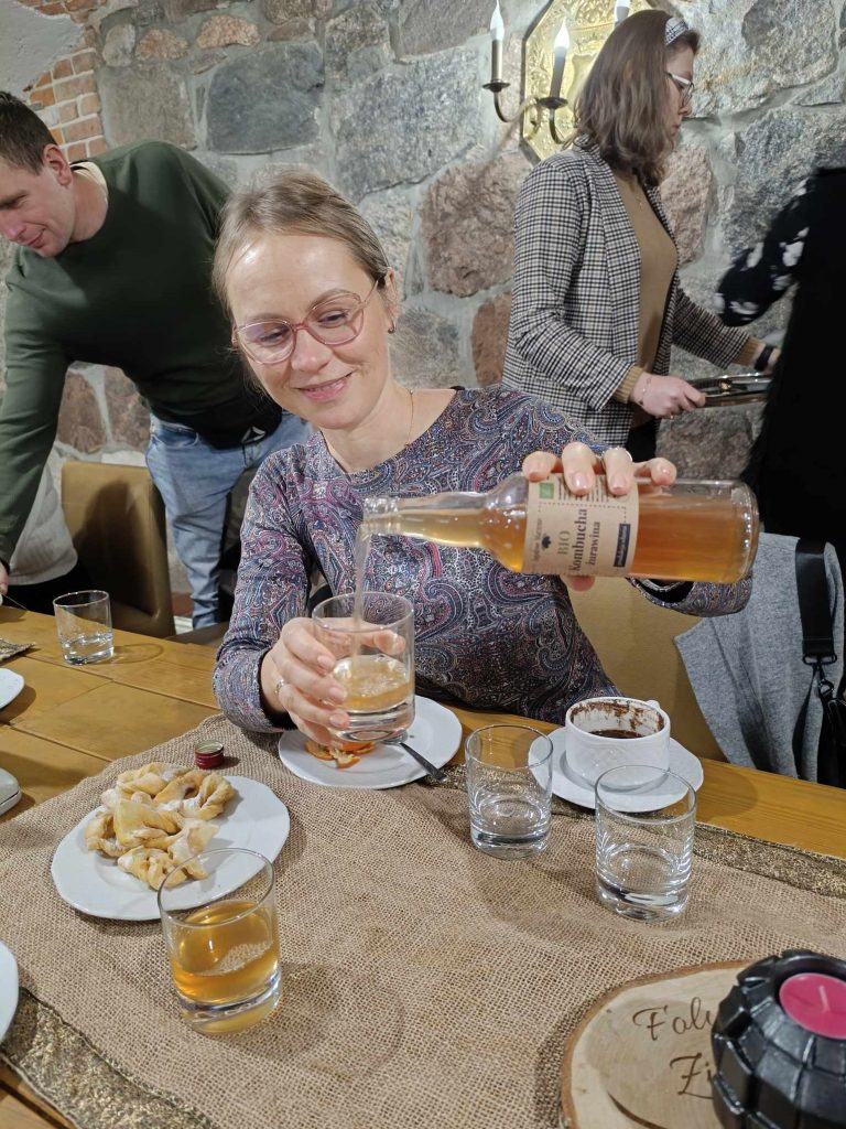 jedna z uczestniczek szkolenia nalewa bio kambuchę, w tle inni uczestnicy