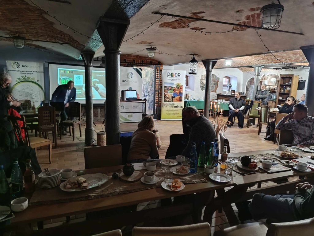 uczestnicy szkolenia na sali wykładowej, w tle slajdy z prezentacją