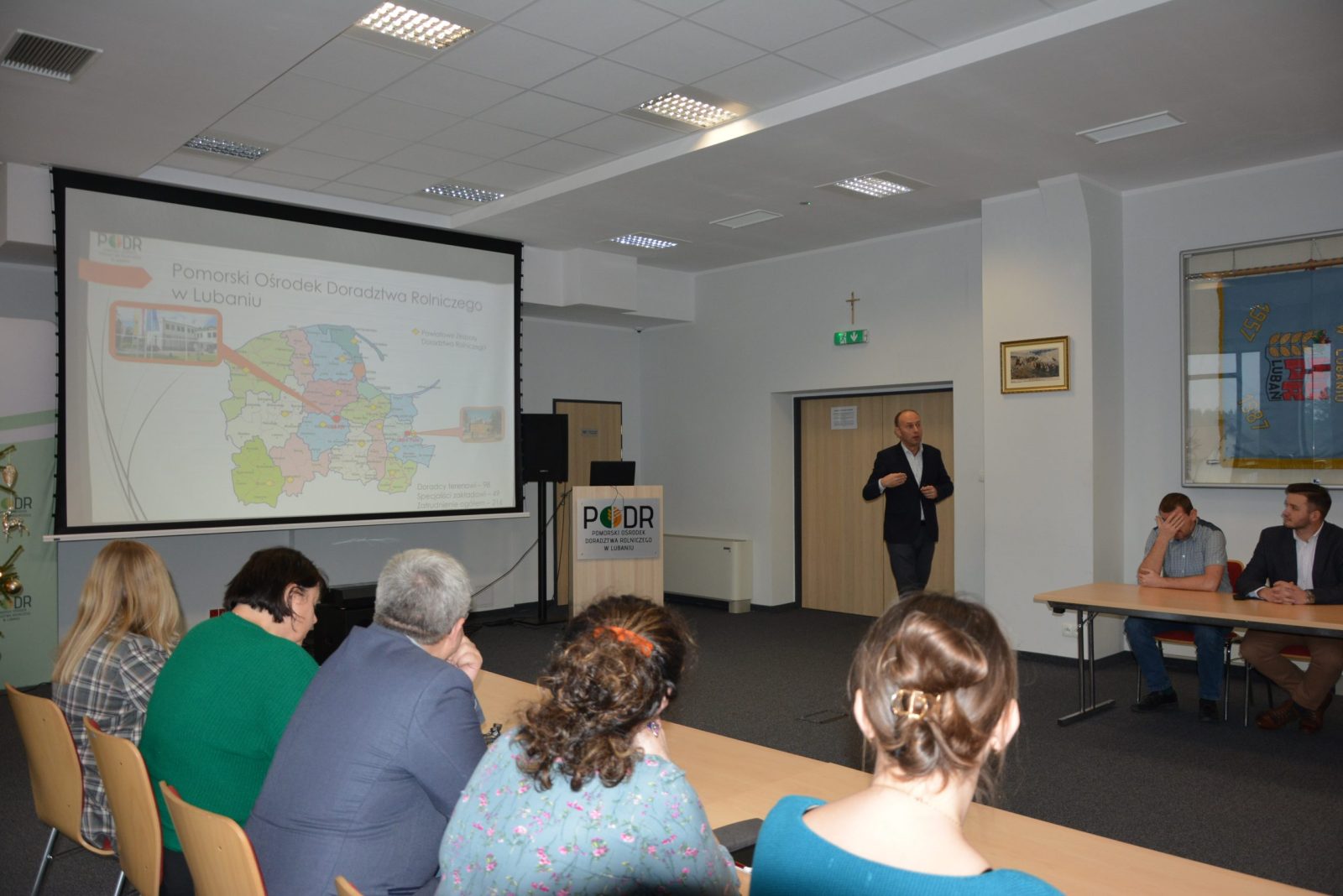 Aleksander Mach, Dyrektor PODR w Lubaniu przedstawia uczestnikom spotkania strukturę organizacyjną Ośrodka. W tle mapa województwa pomorskiego.